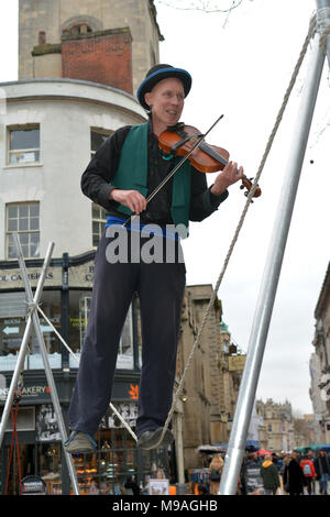 Bristol, UK. 24. März 2018. Ein Nachmittag der Straßenunterhaltung in Wein Straße, Bristol. Eine Performance von slacklining zwischen zwei Pfosten durch die Person spielt eine Violine und gekonnt Balancing beim Gehen auf einem Seil in der Luft ausgesetzt und von Zuschauern verfolgt werden. Robert Timoney/Alamy/live/Aktuelles Stockfoto