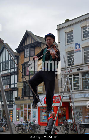 Bristol, UK. 24. März 2018. Ein Nachmittag der Straßenunterhaltung in Wein Straße, Bristol. Eine Performance von slacklining zwischen zwei Pfosten durch die Person spielt eine Violine und gekonnt Balancing beim Gehen auf ein Seil in middair unterbrochen und von Zuschauern verfolgt werden. Robert Timoney/Alamy/live/Aktuelles Stockfoto