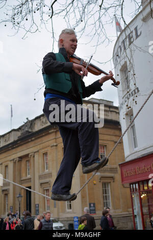 Bristol, UK. 24. März 2018. Ein Nachmittag der Straßenunterhaltung in Wein Straße, Bristol. Eine Performance von slacklining zwischen zwei Pfosten durch die Person spielt eine Violine und gekonnt Balancing beim Gehen auf ein Seil in middair unterbrochen und von Zuschauern verfolgt werden. Robert Timoney/Alamy/live/Aktuelles Stockfoto