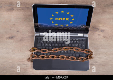 Laptop mit bipr Buchstaben in EU-Sterne auf Holz Hintergrund. Tastatur, die von alten rostigen Ketten gesichert. Schutz persönlicher Daten, Digitalisierung und Bürokratie. Stockfoto