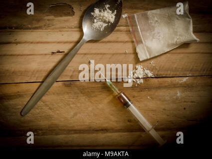 Drogen, Pulver, Spritze und Löffel auf rustikalen Holzfußboden Hintergrund. Drogensucht Konzept Hintergrund mit Platz für Text Stockfoto