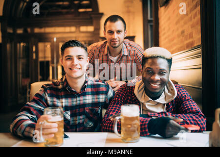 Multirassischen freunde gruppe trinken und toasten Bier im Pub. Junge Menschen die Zeit zusammen genießen und Spaß haben. Stockfoto