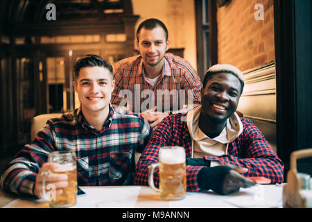 Multirassischen freunde gruppe trinken und toasten Bier im Pub. Junge Menschen die Zeit zusammen genießen und Spaß haben. Stockfoto