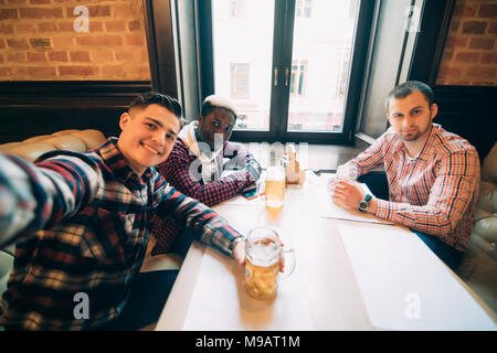 Menschen, Freizeit, Freundschaft, Technologie und Bachelor Party Konzept - glückliche männliche Freunde unter selfie und trinken Bier an der Bar oder pub Stockfoto