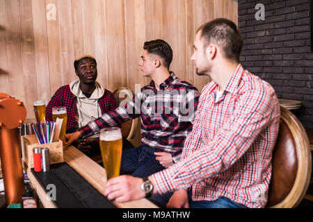 Fröhlich, alte Freunde, Spaß und trinken Bier vom Fass am Tresen im Pub. Stockfoto