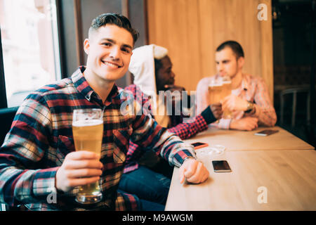 Mann trinkt Bier vor zwei diskutieren trinken Freunden im Pub. Stockfoto