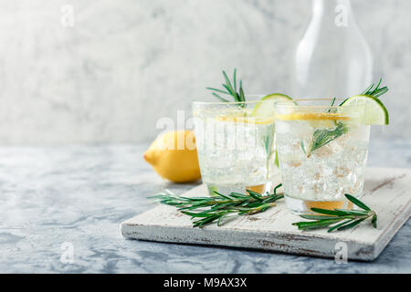 Kalte Limonade oder alkoholfreien Cocktail mit Zitrone, Rosmarin und Eis im Glas Gläser auf einem hellen Hintergrund Stockfoto