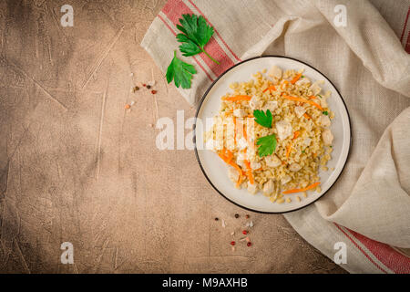 Bulgur Pilaw mit Huhn auf braunem Hintergrund Beton. Ansicht von oben, Platz für Text Stockfoto