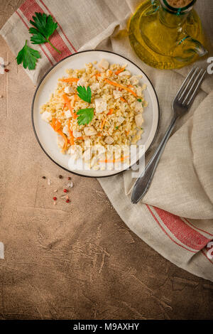 Bulgur Pilaw mit Huhn auf braunem Hintergrund Beton. Ansicht von oben, Platz für Text Stockfoto