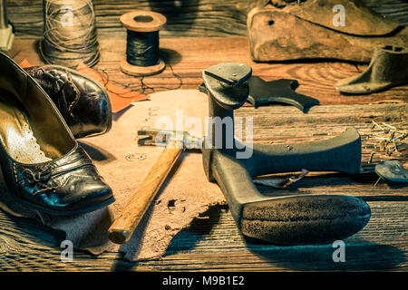 Nahaufnahme der Schuhmacher Arbeitsplatz mit Schuhe, Werkzeug und Spitzen Stockfoto