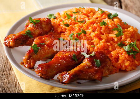 Nigerianische essen Party: Jollof Reis mit Fried Chicken wings Close-up auf einem Teller. Horizontale Stockfoto