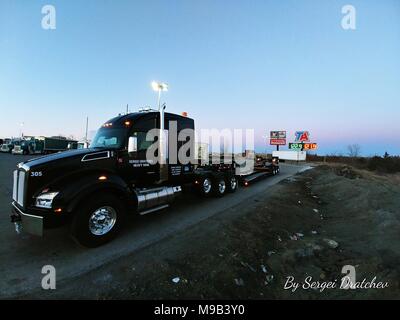 2019 schwarz Kenworth T880 Semi Truck zu einem RGN lowboy Trailer eingehakt, beide neu gewaschen, dargestellt an der TA Truck Stop in Woodstock, ON, Kanada Stockfoto