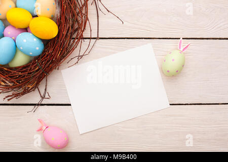 Eier im Nest Ostern traditionelle Objekte auf Holzböden und weißen Blatt Papier mit zwei mit Hasenohren Eier dekoriert isoliert Stockfoto