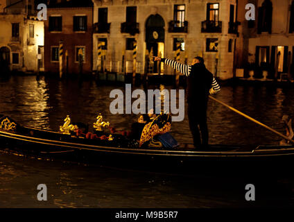 Eine gondiolier weist auf die Sehenswürdigkeiten von Venedig aus einer Gondel über den Canale Grande in der Nähe der Rialto Brücke bei Nacht Stockfoto