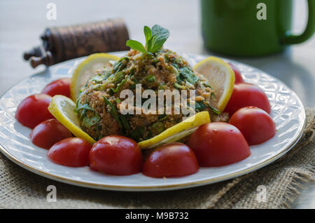 Salat mit Gemüse, Salat, grüne Zwiebeln, Tomatenmark, Öl und Bulgur und Tomaten Stockfoto
