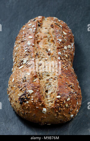 Nahaufnahme von rustikales Vollkornbrot Laib in Backblech auf Schiefer table top Stockfoto