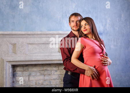 Mann umarmt schwangere Frau von hinten. Er streichelt ihren Bauch. Glück der Elternschaft. Stockfoto