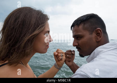 Junges Paar sitzt auf dem Meer. Sie pressen ihre Hände in der Faust. Versprechen einander stark und einander wahr sein. Stockfoto