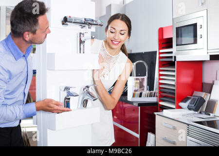 Junge lächelnde Paar heraus spähen hinter der Theke mit Mischbatterie Stockfoto