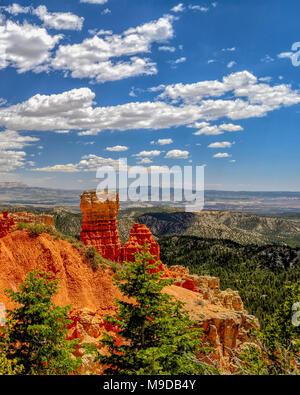 Vertikale Bild mit Blick auf den schönen orangefarbenen Felsen und Klippen mit einem grünen Tal unter einem strahlend blauen Himmel mit weißen Wolken. Stockfoto