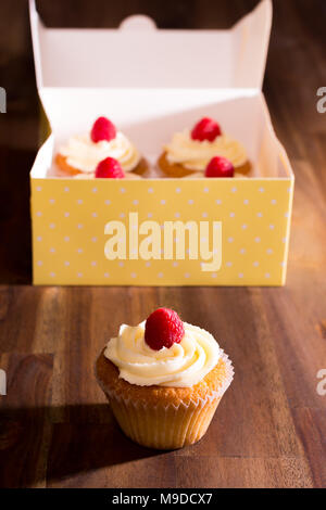 Lemon Cupcakes mit weißer Schokolade Butter gekrönt mit einem frischen Himbeeren Vereisung Stockfoto