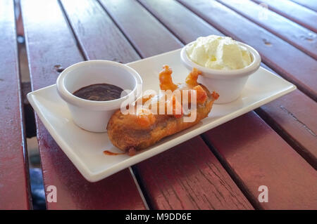 Deep fried Mars bar mit Schokoladensauce und Sahne auf der Seite. Stockfoto