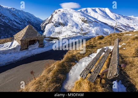 Am Straßenrand Oratorium von Le Chazelet und eine alte Holzbank im Winter. Nationalpark Ecrins, Region PACA, Hautes-Alpes, Alpes, Frankreich Stockfoto