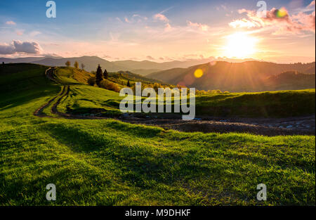 Kurvenreiche Straße entlang der grasartigen ländliche Hügel bei Sonnenuntergang. wunderschöne Landschaft der Karpaten Gebirge im Frühling Stockfoto