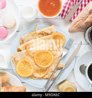 Crepes Suzette auf blauen Platte, Marmelade, Baguette, Kaffee und macarons. Traditionelles französisches Frühstück. Ansicht von oben, Quadrat Erntegut Stockfoto