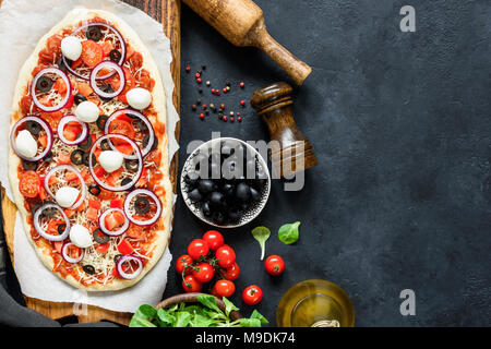 Pizza kochen. Hausgemachte Pizza. Zubereitung von Pizza. Ansicht von oben mit der Kopie Platz für Text, dunklen Stein Schiefer Hintergrund Stockfoto