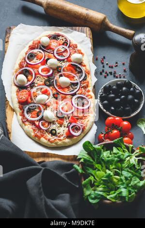 Hausgemachte Pizza mit schwarzen Oliven, Mozzarella, lila Zwiebeln und Tomatensauce. Vertikale, Ansicht von oben Stockfoto