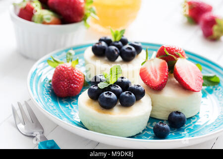 Mini Käsekuchen mit frischen Erdbeeren und Blaubeeren auf blauen Platte, Detailansicht. Syrniki, Quark Pfannkuchen Stockfoto