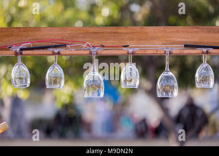 Mehrere Weingläser hing auf einer Platine in einem Gartenrestaurant. Stockfoto