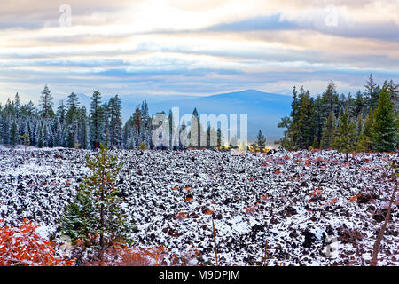 43,043.07696 winter schnee auf einer breiten groben Flachbild Lavastrom Nadelbäumen Wald Berge im Hintergrund, dramatische bewölkter Himmel, Sonne Akzente ein entferntes Tal Stockfoto