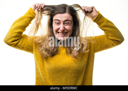 Eine junge Kaukasier Frau Mädchen mit einem gelben Pullover Pullover, schauen, frustriert und verärgert, ihr Haar ziehen gegen einen weißen Hintergrund, Großbritannien Stockfoto