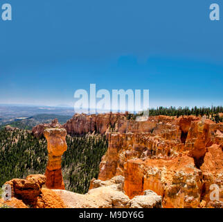 Aussichtspunkt an einem Hoodoo und verschiedene orange und rote Felsformationen mit einem grünen Tal unten unter blauen Himmel mit Wolken. Stockfoto