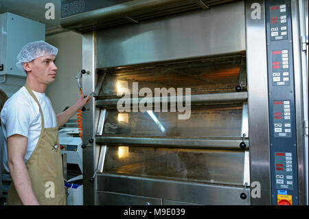 In der Bäckerei: Bäcker steht in der Nähe von elektrischer Ofen für Arbeit bereit. März 21, 2018. Brovary, Ukraine Stockfoto