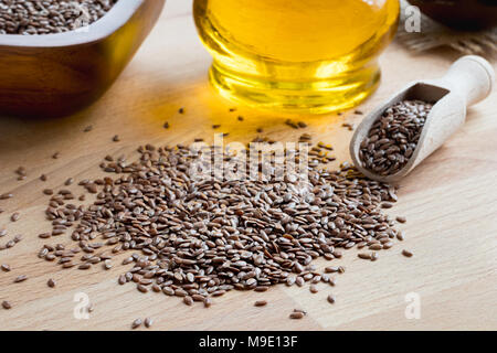 Leinsamen auf einen hölzernen Tisch, mit Leinsamen öl im Hintergrund Stockfoto