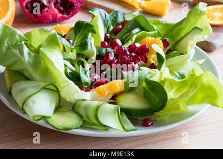 Salat auf einen Teller - Kopfsalat, Feldsalat, Gurke, Avocado, Orange, Granatapfel Stockfoto