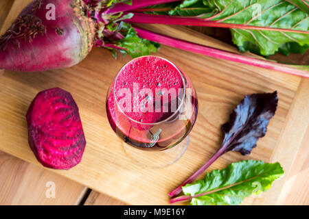 Rote Bete Saft in ein Glas Wein mit ganzen Rüben auf einem Holztisch Stockfoto