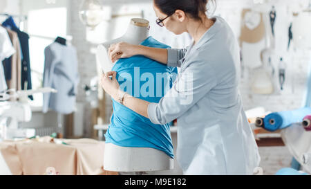 Schöne weibliche Mode, Designer, Einstellung der Gewebe auf eine maßgeschneiderte Schaufensterpuppe. In ihrem Atelier verschiedene Nähen und farbenfrohen Stoffen zur Um Stockfoto