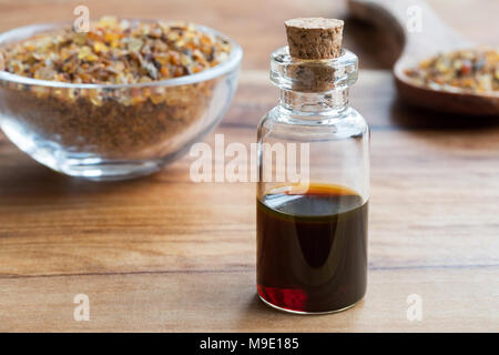 Eine Flasche Myrrhe ätherisches Öl auf einem Holztisch mit Myrrhe Harz im Hintergrund Stockfoto