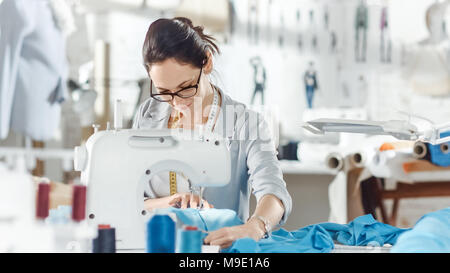 Weibliche Mode, Designer,/Näherin/Schneiderin arbeitet an einer Nähmaschine in Ihr Sonniges Studio. Verschiedene Nähen Gegenstände und Stoffe zur Festlegung um Sie herum Stockfoto