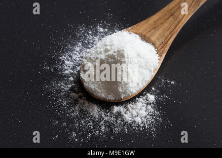 Natron (Natriumbicarbonat) auf einem Löffel aus Holz auf einem dunklen Hintergrund Stockfoto