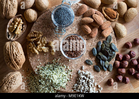 Nüsse und Samen - Walnüsse, Mandeln, Leinsamen, Haselnüsse, Hanf, Kürbis- und Sonnenblumenkerne. Ansicht von oben. Stockfoto