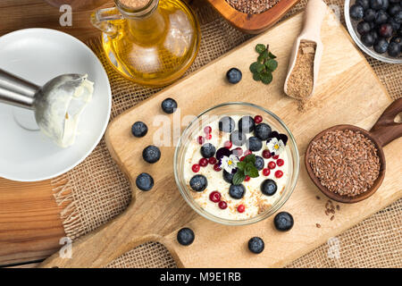 Hüttenkäse Gemischt mit Leinsamen öl, gekrönt mit Blaubeeren, wilde Preiselbeeren, essbare Blumen und Boden Leinsamen Stockfoto