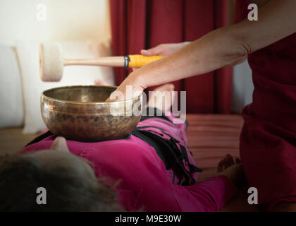 Frauen legen sich auf den Boden, die eine entspannende Tibetische Klangschale klang Heilung. Stockfoto