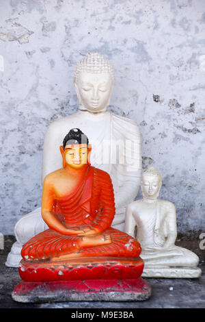 Verschiedene Gips Statuetten von Buddha in einem baufälligen kleinen Straßenrand Heiligtum in Sri Lanka Stockfoto