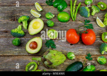 Grüne Smoothies und Zutaten - Avocado, Apfel, Gurke, Kiwi, Zitrone, Dill, Sellerie, Brokkoli, gesundes Kochen oder Salat mit rustikalen Olivenholz Stockfoto