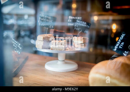 Flapjack und Kuchen Auswahl auf einem Display auf einem Kuchen stehen in einer Bäckerei Fenster in Großbritannien Stockfoto